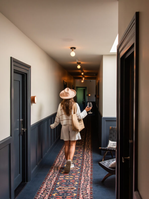 Woman walking down a hallway at El Dorado Hotel holding a tote bag